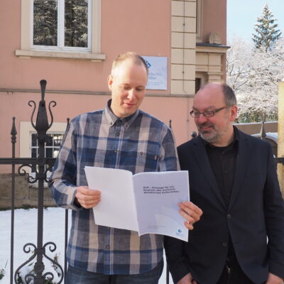 Alf-Christian Schering und Dr. Robert Lorenz (v.l.), Informatiker und Ethnologe am Sorbischen Institut, blicken in das soeben überreichte Konzept für ein Register des sorbisch-wendischen Kulturerbes © SI (2023)