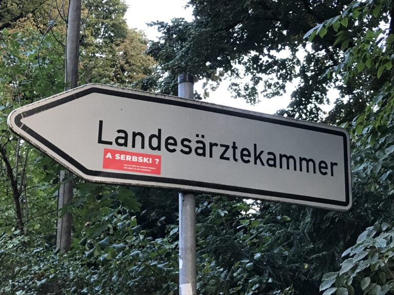 A serbski? [Und auf Sorbisch?] – lautet die Frage auf den roten Aufklebern, die seit einer Weile an vielen Stellen in Cottbus zu sehen sind, meistens auf Schildern und Plakaten mit einsprachiger deutscher Aufschrift. © Sorbisches Institut/Simon Blum (2022)