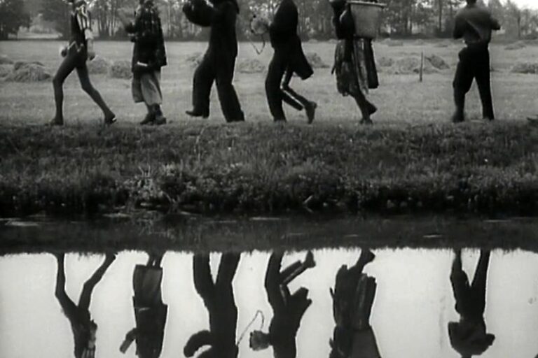Sechst Personen (angeschnitten) laufen an dem Fluss Struga entlang und spiegeln sich auf der Wasseroberfläche. Motiv aus dem Schwarz-Weiß-Film aus dem Jahr 1972