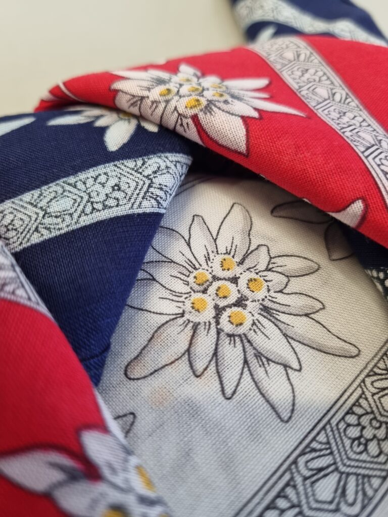 Das Bild zeigt drei Tücher mit Edelweiß-Motiven. Die Tücher sind in den Farben der sorbischen Flagge, blau, rot und weiß.